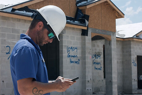 - Housecall Pro construction worker in hardhat using phone at job site